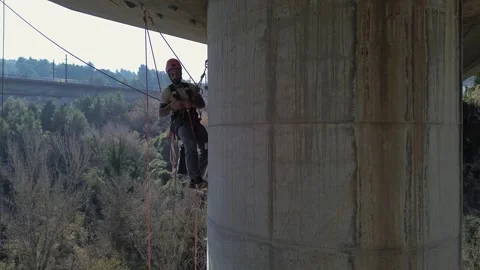 Rope access technician performing maintenance on bridge pylon Stock Footage 306669601