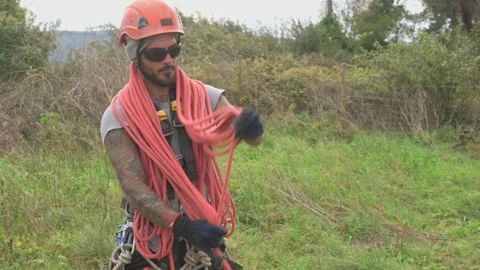 Rope access technician preparing climbing rope for tree pruning Stock Footage 302874937