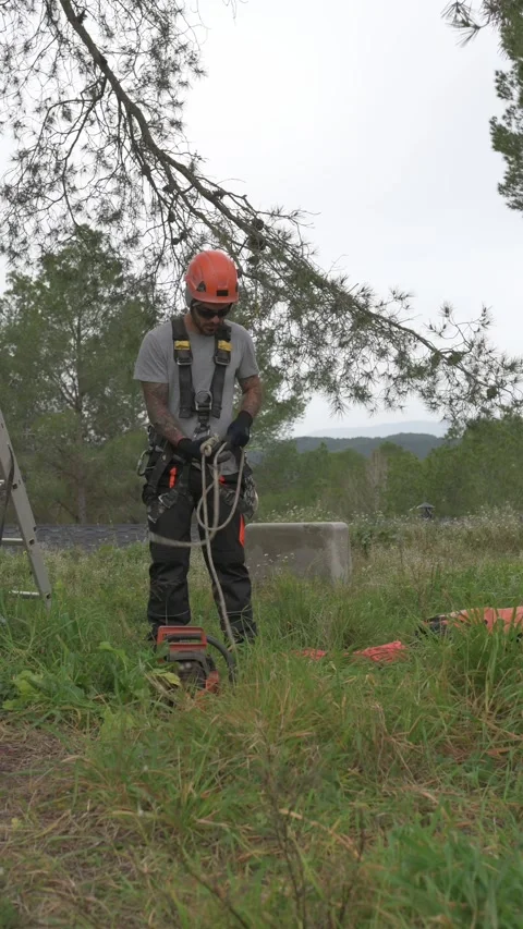 Rope access technician preparing equipment for tree pruning Stock Footage 302960324