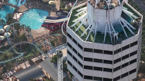 Rope access technicians cleaning skyscraper windows next to waterpark Vídeo Stock 330339235