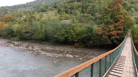 Rope bridge, across the ski river, spring, mountains, landscape, houses Stock Footage 145697565