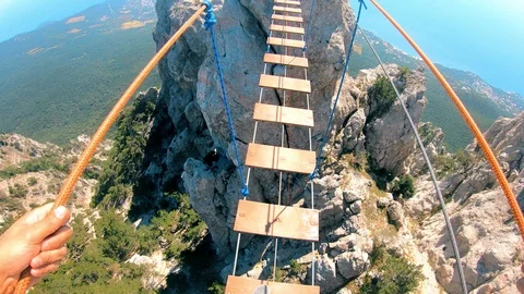 Rope bridge.A man goes between the rocks.Extreme tourism. Stock Footage 95400822