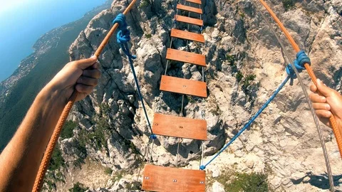 Rope bridge stretched between the rocks.The man carefully crosses the bridge. Stock Footage 95548496