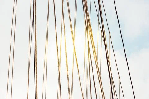 Rope cables against cloudy sky create industrial abstract pattern, background Stock Photos