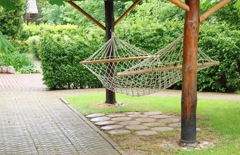 Rope hammock between trees in park. Holidays in nature. Rest and enjoyment. Stock Photos