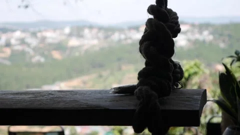 Rope knot on a motionless swing, with mountain village in the distance. The Stock Footage 312109293