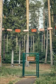 Rope park with high rope courses on pine trees and fence with closed gate Stock Photos