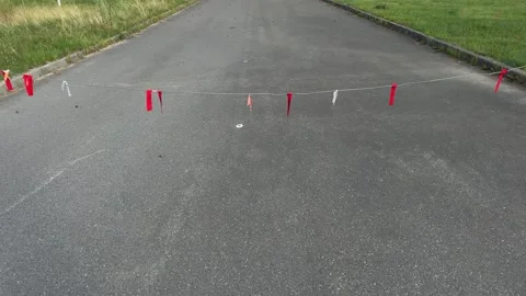 Rope with red and white flags stretched across asphalt road  Stock Footage 340515246
