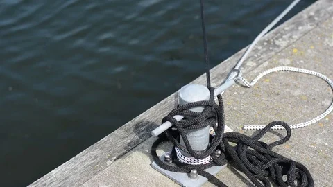 Ropes around a bollard on a pier next to the water Stock Footage