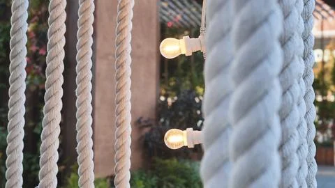 Ropes creating texture and pattern with glowing light bulbs for outdoor ambiance Stock Photos
