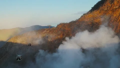 Ropeway cabins moving through volcanic steam and mountains in Hakone, Japan Видео 335027988