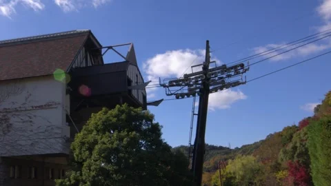 Ropeway gondolas pass through mid mountain station on autumn day Stock Footage 327631383