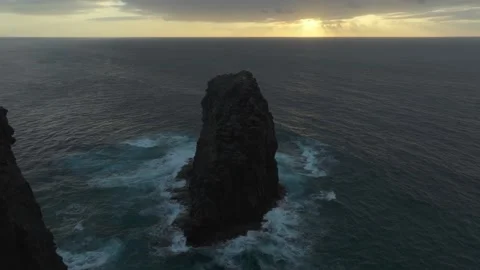 Roque del Farallon sea stack silhouetted at sunset, Gran Canaria aerial view Stock Footage 347516887