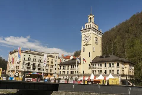 Rosa Khutor. The clock tower on the central square. Town hall. People walk ar Stock Photos