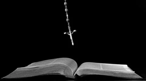 Rosary beads falling onto open bible Stock Footage
