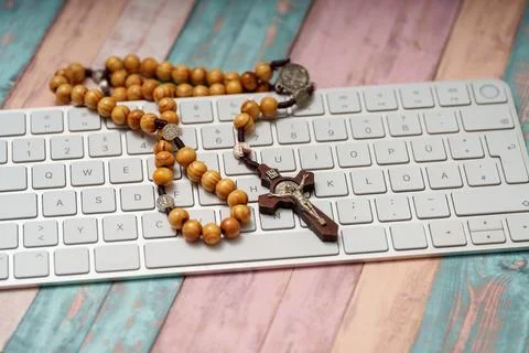 Rosary placed on a computer keyboard during online prayer at home in the af.. Foto stock