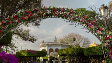 Rose arch in Comitán's central park, Mexico, frames the kiosk and church at Stock Footage 308218032