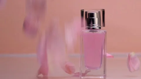 Rose petals fall on a perfume bottle on a beige background 스톡 동영상 154707651