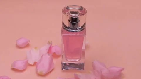 Rose petals fall on a perfume bottle on a pink background Stock Footage 154707667