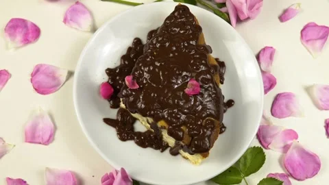 Rose petals fall on a piece of a cottage cheese pie with chocolate icing. top vi Stock Footage 337403178