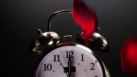 Rose petals falling on dual bell alarm clock representing love and Valentine's D Vidéo 208533784