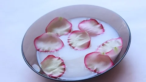 Rose petals float in milk. Video of flower petals in milk. Milk in the plate. Video stock 106567634