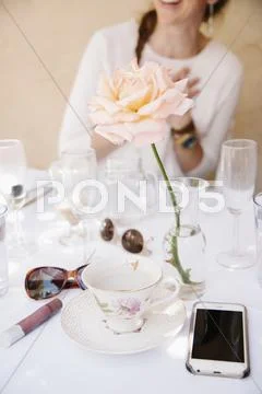 Rose in a vase on a table with cups and glasses Stock Photos