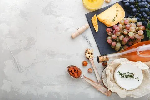 Rose wine bottle cheese nuts and pink and black grapes on slate board and honey Foto stock