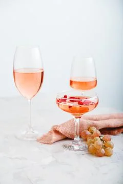 Rose wine in different types of glasses on light concrete background with grapes Stock Photos
