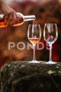 Rose wine pouring from a bottle to a glass in the nature. Stock Photos