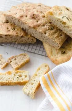 Rosemary focaccia on a white surface and yellow kitchen towel Stock Photos