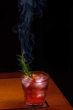 Rosemary smoked negroni cocktail. Negroni cocktail glass on wooden table with Stock Photos