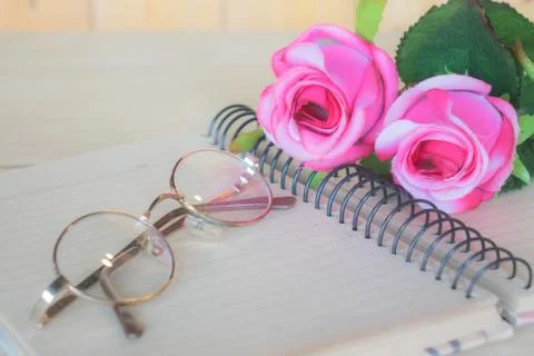 Roses on a notebook with glasses. Stock Photos