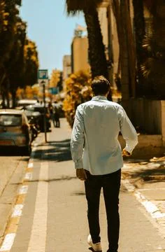 ROSH PINNA, ISRAEL - May 24, 2021: A rear view of man walking along a street  Stock Photos