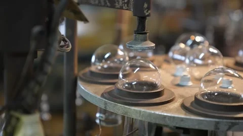 Rotary carousel machine holding clear glass bulb domes ready for processing Stock Footage 345399131