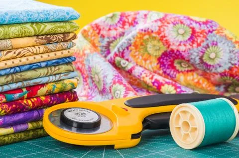 Rotary cutter and spool of thread on a background fabric Stock-Fotos