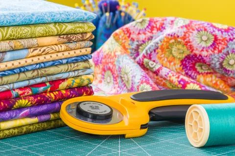 Rotary cutter and spool of thread on a background fabric Stock-Fotos