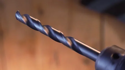 Rotary Drill Bit in Focus Against Blurred Wooden Workshop. Stock Footage 257490064