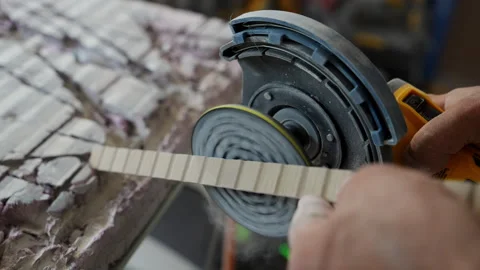 Rotary sander smoothing the edge of a ceramic or stone tile. Dust particles rise Stock Footage 320448220