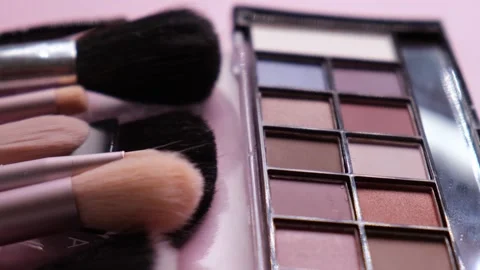 Rotate background with makeup brushes and eyeshadow palettes on pink background Stock Footage 246874799