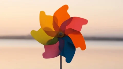 A rotate colored plastic pinwheel with a blowing wind stands on sand by the sea Stock Footage 105688322