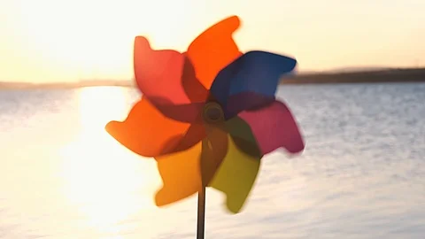 Rotate colored plastic pinwheel with blowing wind stands on sand by sea Stock Footage 105688501