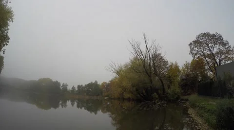 Rotated view of small pond surrounded by broadleaf trees with fog Video stock 56473066