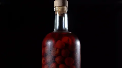 Rotates cold cherry brandy drink with red cherries on black background, macro Stock Footage 94148409