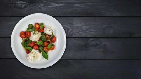 Rotates salad on a plate. Mozzarella with grilled cherry tomatoes, pesto sauce Stock Footage 128537511