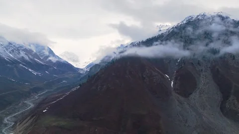Rotating Aerial View of Low Hanging Clouds clinging to Rugged Alpine Slopes 스톡 동영상 332978721