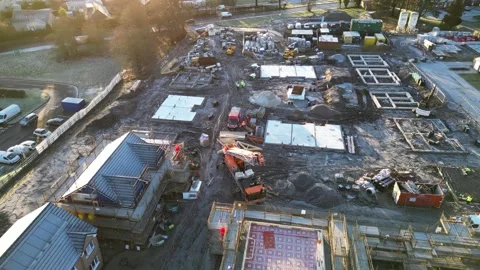Rotating Aerial View of UK Construction Site with Surrounding Homes and Nature Stock Footage 261696776