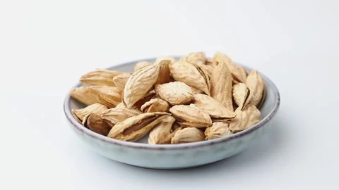 Rotating of almonds in ceramic plate on white background. Side view. Stock Footage 136050286