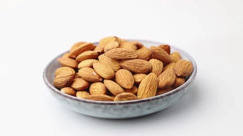 Rotating of almonds in ceramic plate on white background. Side view. Stock Footage 136050290