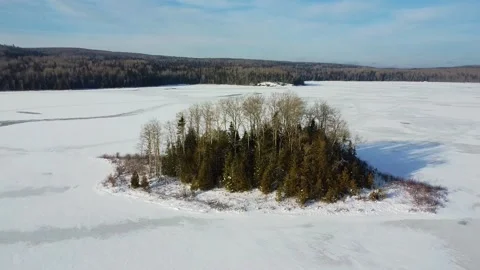 Rotating around a island full of trees on a large,completely frozen lake. Stock Footage 303678254